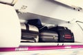Hand-luggage compartment with suitcases in airplane. Carry-on luggage on top shelf of plane. Travel concept with copy