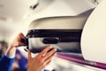 Hand-luggage compartment with suitcases in airplane. Hands take off hand luggage. Passenger put cabin bag cabin on the Royalty Free Stock Photo