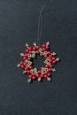 hand made beads red and gold star Christmas ornament on a black glitter background Royalty Free Stock Photo