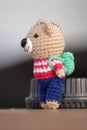 Hand made key ring brown teddy bear knitted doll wearing a red and white shirt and blue plant Royalty Free Stock Photo