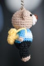 Hand made key ring teddy bear knitted doll wearing a blue and white shirt and black planm Royalty Free Stock Photo