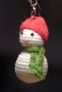 Hand made key ring snowman knitted doll wearing a red hat and green scarf Royalty Free Stock Photo