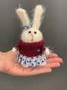 Hand made knitted toy rabbit or hare standing on the hand. Beautiful girl toy for children