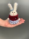 Hand made knitted toy rabbit or hare standing on the hand. Beautiful girl toy for children
