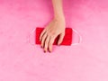 Red face mask in female hand on pink. Covid-19 Royalty Free Stock Photo