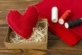 Hand made red felt heart, thread, cloth on wooden background