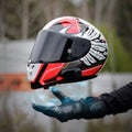 Hand magically holds a motorcycle sports helmet. Close up. Hand in a leather glove