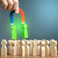 A hand with a magnet pulls green figures of people out of the crowd. Recruiting new workers. Formation of a new team. Search