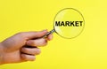 Hand with magnifier with word market on yellow background. Conducting research about new product, service, customers Royalty Free Stock Photo