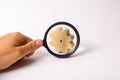 Hand with the magnifying glass is aimed at the wooden wheel gear. concept of studying the technological process and industry Royalty Free Stock Photo