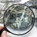 Hand with magnifying glass examines asbestos fibers Royalty Free Stock Photo