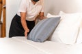 Hand of maid setting up pillow on bed sheet in hotel room Royalty Free Stock Photo