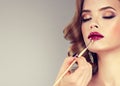 Hand of make-up master, painting lips of model. Royalty Free Stock Photo