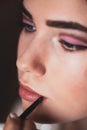 The work of a professional makeup artist. Hand of make-up master, painting lips of young beautiful model Royalty Free Stock Photo