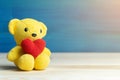 Hand make yarn red heart put on yellow teddy bear in front of white pot and green ornamental plants on wooden table and blue backg Royalty Free Stock Photo