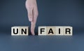 Hand makes the word unfair into fair from the cubes. The concept of social problems in society