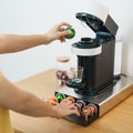 hand making Espresso Coffee by Coffee Maker Machine with Capsule of roasted coffee bean on wood table bar. Daily beverage drink at Royalty Free Stock Photo