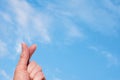 A hand making a heart shape with two fingers against the background of a blue sky with white fluffy clouds. Royalty Free Stock Photo