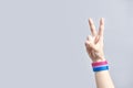 Hand making the victory sign wearing a bracelet with the bisexual flag colors Royalty Free Stock Photo