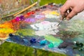 Hand of a male artist mixing white paint on an old palette outdo Royalty Free Stock Photo