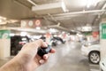 Hand male asia ,holding car remote on Blurred image parking in t