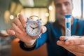 The hand of a male businessman holds a clock alarm time and an hourglass, close-up Royalty Free Stock Photo