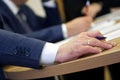 Hand of a male executive holding a fountain pen during a meeting or discussion. Decision making. Filling out documents,