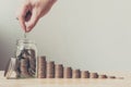 Hand of male or female putting coins in jar with money stack ste Royalty Free Stock Photo