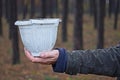 the hand of a male gardener holds a big bey dirty plastic flowerpot