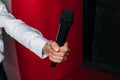 the hand of a male journalist holds a microphone on a red background Royalty Free Stock Photo