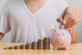 Hand of male putting coins in piggy bank with money stack step growing growth saving money. Concept finance business investment Royalty Free Stock Photo