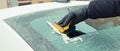 Hand of man using yellow scraper to remove ice from window in car, winter problems Royalty Free Stock Photo