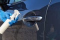 Hand of man in blue protective glove is spraying disinfectant on handle of car door. Coronavirus or Covid-19 protection Royalty Free Stock Photo