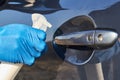 Hand of man in blue protective glove is spraying disinfectant on handle of car door. Coronavirus or Covid-19 protection Royalty Free Stock Photo