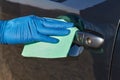 Hand of man in blue protective glove is wiping with a cloth an exterior handle of car door. Coronavirus or Covid-19 protection Royalty Free Stock Photo