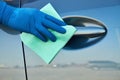 Hand of man in blue protective glove is wiping with a cloth an exterior handle of car door. Coronavirus or Covid-19 protection Royalty Free Stock Photo