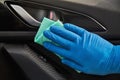 Hand of man in blue protective glove is wiping with a cloth an interior handle of car door. Coronavirus or Covid-19 protection Royalty Free Stock Photo