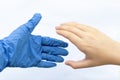 The hand of a man in blue sterile gloves greets the hand of a man without gloves on a white background. The concept of protection Royalty Free Stock Photo