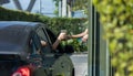 Hand Man in car receiving coffee in drive thru fast food restaurant. Staff serving takeaway order for driver in delivery window. D