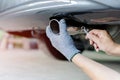 Hand man catch car exhaust and use open-end wrench for service in concept maintenance car in garage Royalty Free Stock Photo