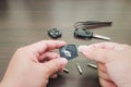 Close up Hand a man change batteries of car key and repair concept on wood table background with screwdrivers and pliers