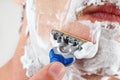 Hand man with a disposable razor shaving his face closeup Royalty Free Stock Photo