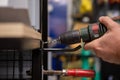 The hand of a man drilling a hole with a drill. He mounts a shelf in a tool and accessories store for the building. Copy Space Royalty Free Stock Photo