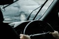 The hand of a man driving on the road on a rainy day. hands of a man with car steering wheel is ready on the move in the modern