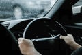 The hand of a man driving on the road on a rainy day. hands of a man with car steering wheel is ready on the move in the modern