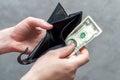 Hand of a man with an empty wallet and two American dollars close-up. Concept of poverty, economic crisis