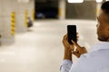 Hand of man hold mobile phone over blurred car parking with bokeh light Background Royalty Free Stock Photo