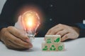 Hand man holding bulb light and wood cube green eco environmental and net zero concept