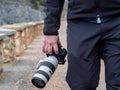 Hand of a man holding a camera outdoors in the middle of a path