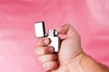 Hand of a man holding cigarette lighter against light pink. Royalty Free Stock Photo
